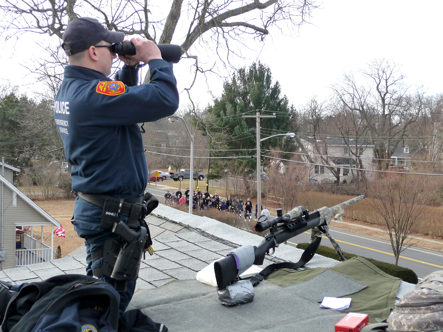 an officer on top of a building with a sniper rifle